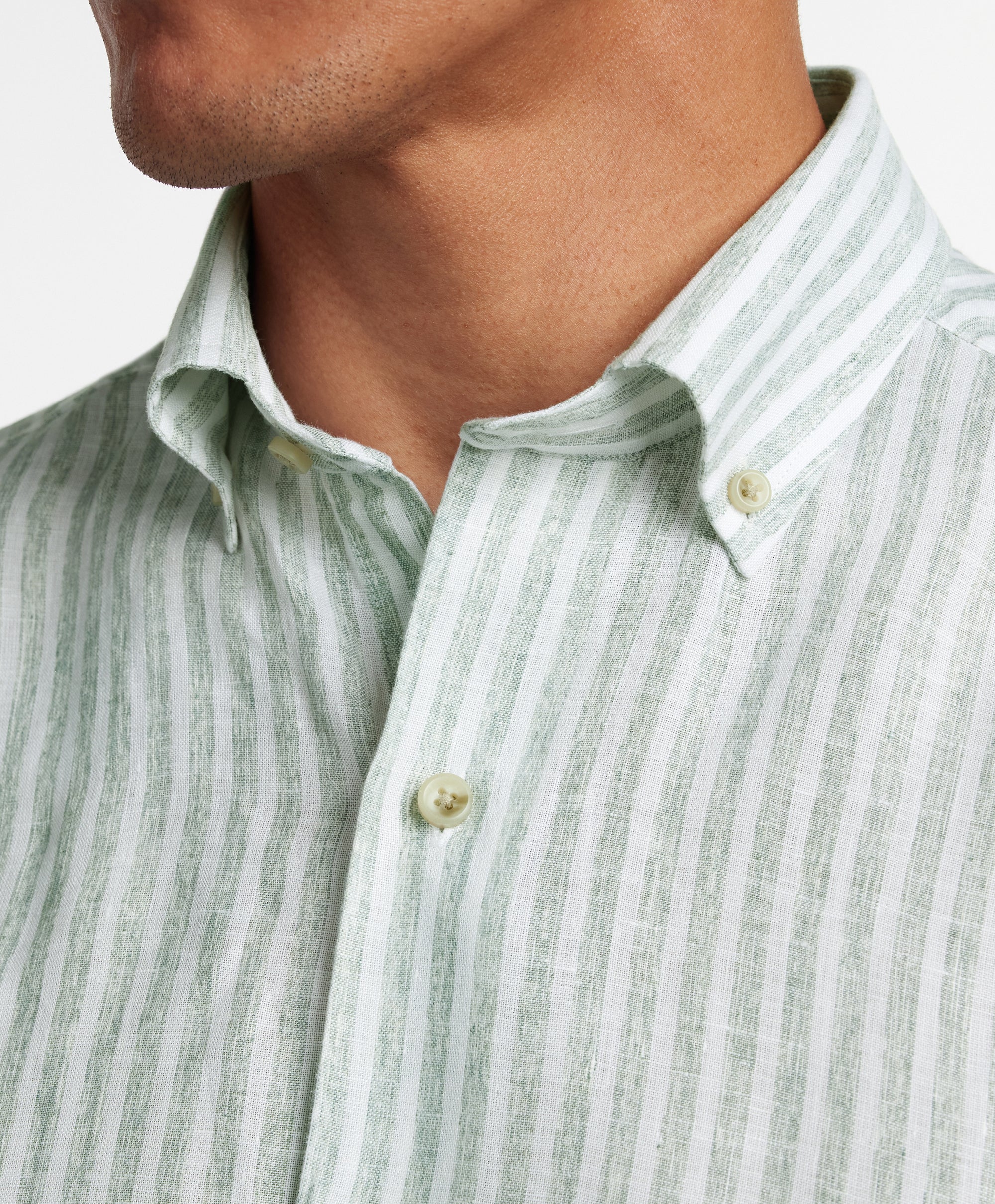 A close-up of a person wearing the David Donahue Linen Stripe Sport Shirt (CBBD12955335) featuring sage and white stripes in a classic button-down style.