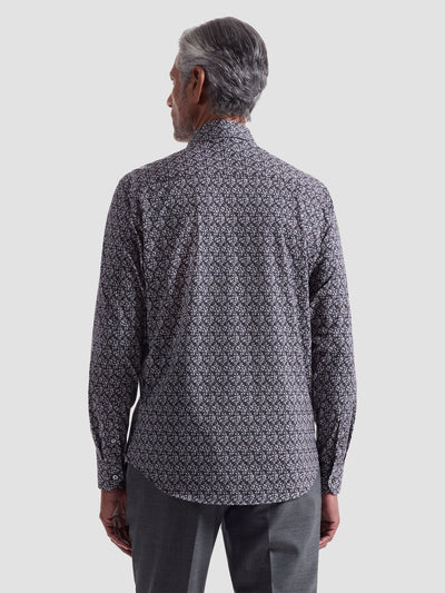 A man with gray hair, facing away, wears the Bugatchi James Leaf Print Sport Shirt HF9221K60 and gray trousers against a plain light background.