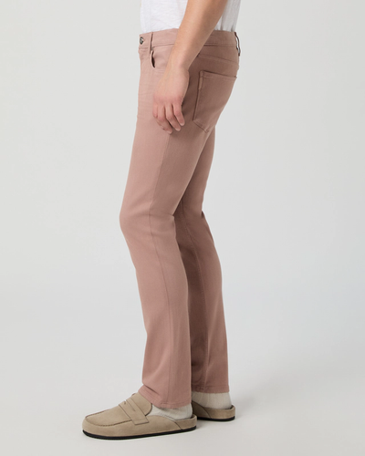A person wearing Paige Federal Slim Straight Jeans in light pink by Paige, paired with a white shirt and beige shoes, standing against a plain light background.