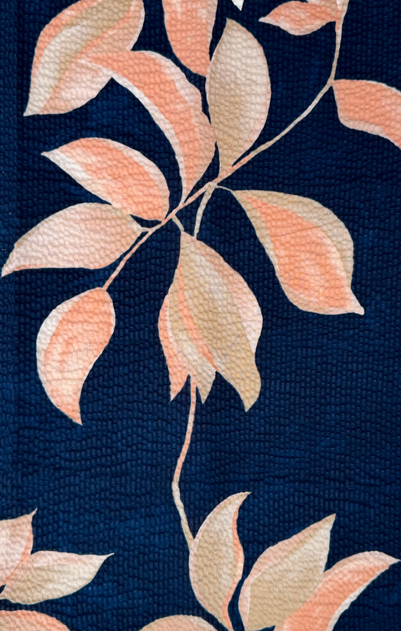 The Tori Richard Textured Fresco De Cas Shirt (1956M0387) by Tori Richard features a dark blue textured background adorned with peach and beige leaves and vines, crafted from breathable cotton pucker lawn and proudly made in Hawaii.