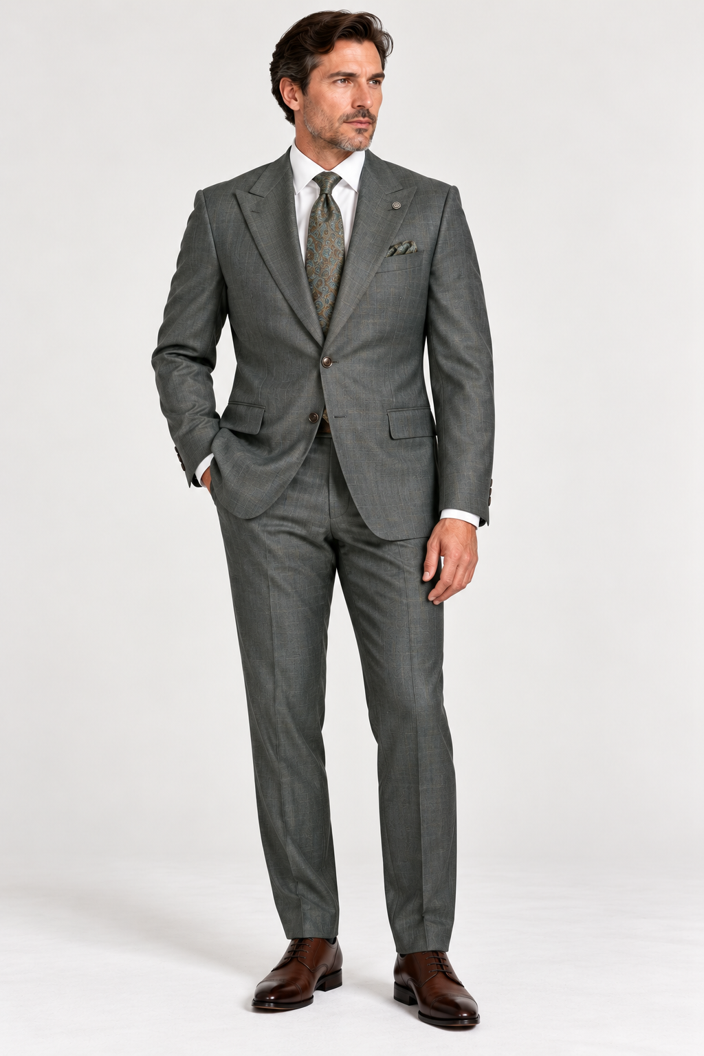 Man wearing a Jack Victor Engel Olive Slim Fit Suit 3262602 in grey plaid, white dress shirt, and patterned tie with brown leather dress shoes.