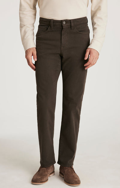 A person wears a cream long-sleeve shirt, brown suede shoes, and 34 Heritage Charisma Diagonal Big&Tall burgundy twill pants by 34 Heritage, standing against a plain background.