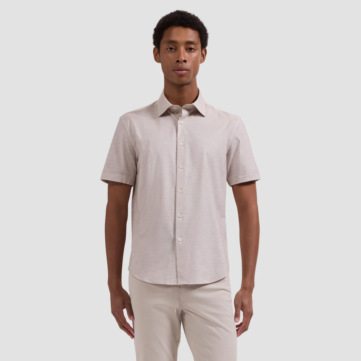 A man faces forward wearing the Bugatchi Miles OoohCotton® Melange Shirt JF9505F40 in light beige, paired with matching pants, against a plain background.