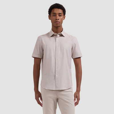 A man faces forward wearing the Bugatchi Miles OoohCotton® Melange Shirt JF9505F40 in light beige, paired with matching pants, against a plain background.