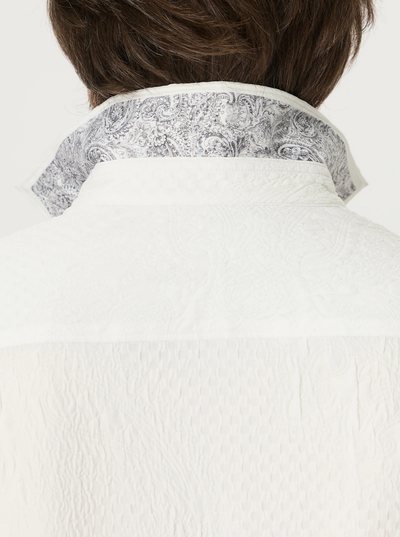 Close-up of the back of a person wearing the Robert Graham Devonshire Woven Shirt, a white long-sleeve style with the collar turned up to reveal a gray and white floral paisley jacquard pattern on the inside—a signature detail from Robert Graham.