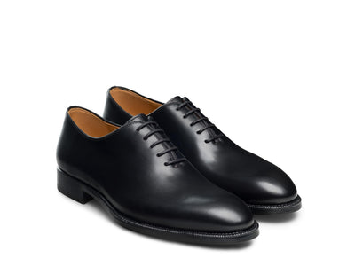 A pair of Magnanni Hawkins Wholecut Oxford dress shoes in black calfskin, featuring closed lacing, low heels, and stitched soles, displayed on a white background.