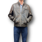 A man wearing a brown Missani leather jacket with a crew neckline and long sleeves, paired with blue trousers. The jacket features a zipper closure and multiple pockets.