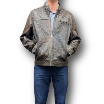 A man wearing a brown Missani leather jacket with a crew neckline and long sleeves, paired with blue trousers. The jacket features a zipper closure and multiple pockets.
