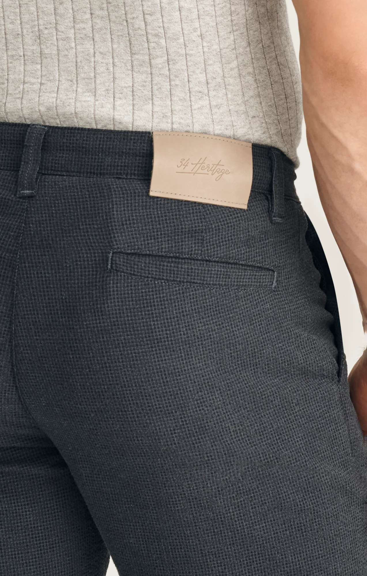 Close-up of a person wearing 34 Heritage Arizona Seersucker Shorts in dark, textured, breathable fabric with a beige 34 Heritage label on the waistband, paired with a light ribbed shirt.
