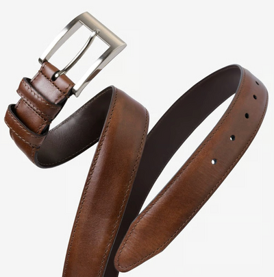 The Allen Edmonds Wide Basic Belt by Allen Edmonds is shown coiled and unbuckled against a plain white background. This brown leather dress belt is handcrafted in America from premium Italian calfskin and features a silver buckle.
