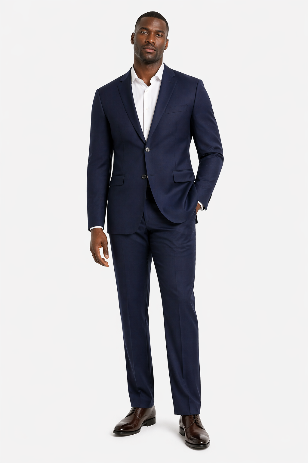 A man stands against a white background wearing the Baroni Big & Tall Suit Notch Lapel by Baroni, paired with a white dress shirt and dark brown dress shoes.