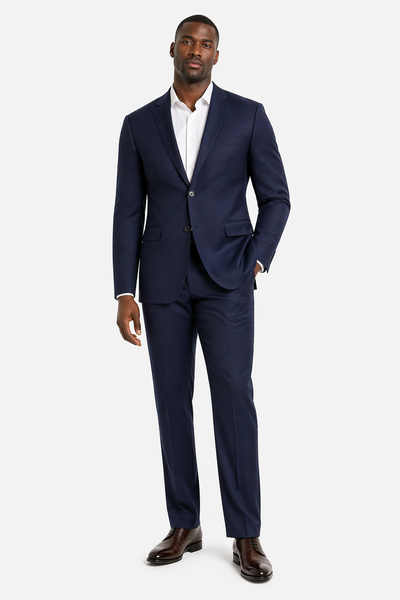A man stands against a white background wearing the Baroni Big & Tall Suit Notch Lapel by Baroni, paired with a white dress shirt and dark brown dress shoes.