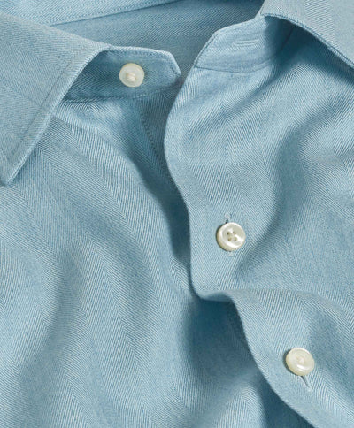 The David Donahue Herringbone Sport Shirt (CBSM10100) is a light blue Pima cotton shirt with a herringbone weave, white buttons, and adjustable cuffs, shown partially unbuttoned in close-up.