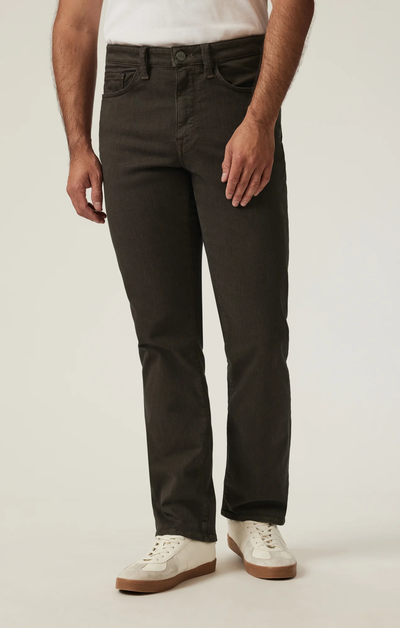 A man wearing 34 Heritage Charisma Diagonal Big&Tall trousers from 34 Heritage, a white t-shirt, and white sneakers stands against a plain light background.