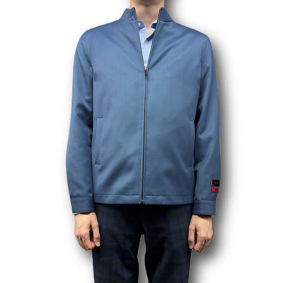 A person wears a light blue Mattarazi Coat Paolo by Mattarazi over a matching collared shirt and dark plaid pants, standing against a plain white background.