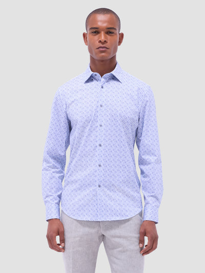 A man wears the Bugatchi LS Jules GF9090K65 Air Blue patterned long-sleeve shirt and light gray pants, standing facing forward against a plain light gray background.