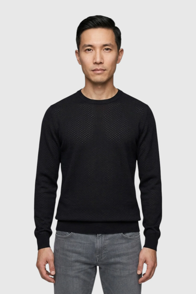 A man stands facing forward, wearing the Garnet Upton Merino Ribbed Crewneck Sweater 2622002 in black and grey jeans against a plain light grey background.