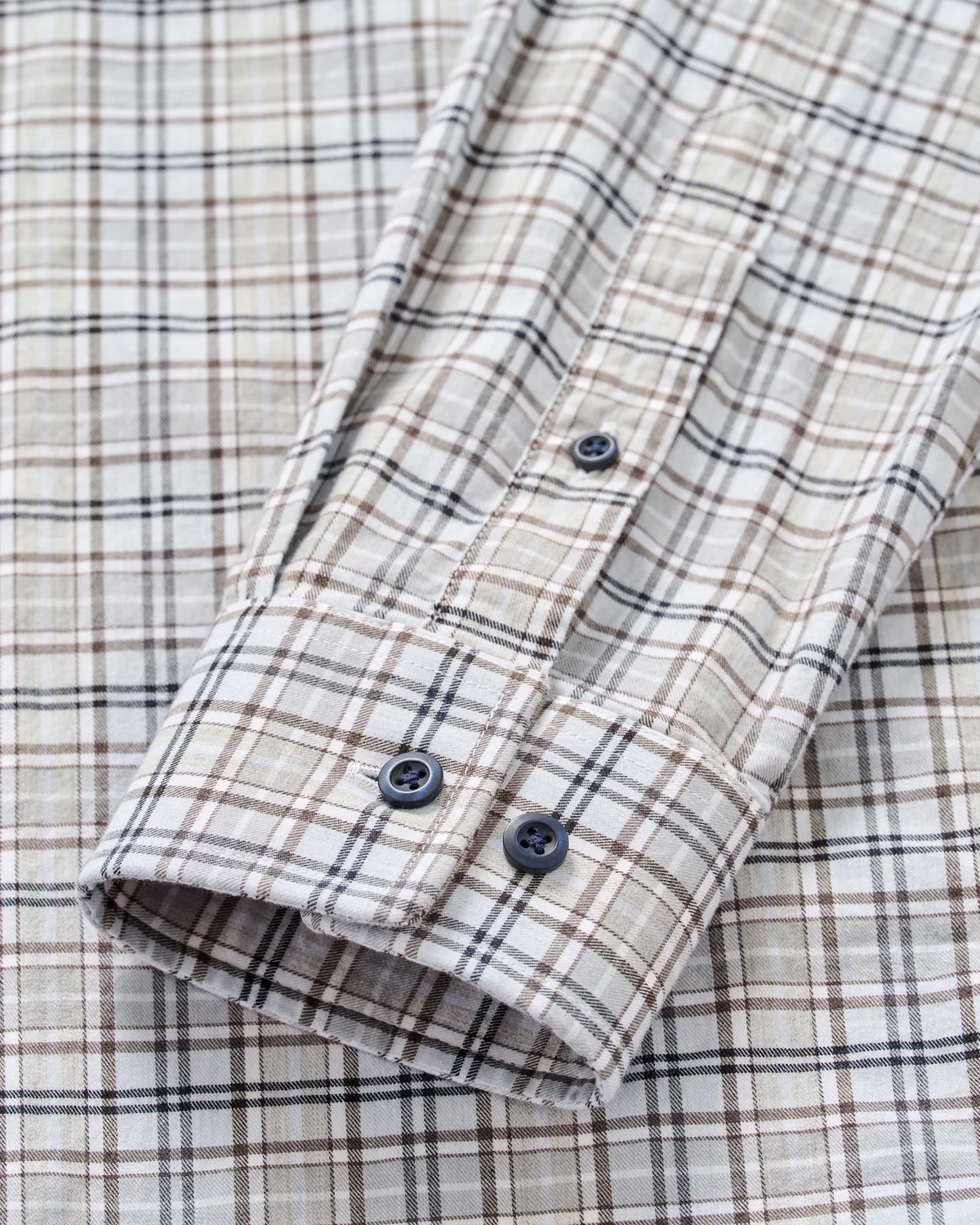 Close-up of the Johnnie-O Tahoe Plaid Flannel Shirt Big & Tall, a men’s shirt by Johnnie-O featuring a beige, brown, and black plaid pattern with a detailed view of the cuff and two black buttons.