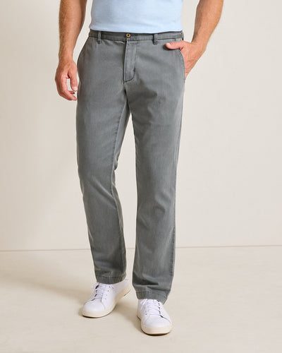 A man wearing Tommy Bahama Boracay Pant Big & Tall chinos in light gray stands against a plain light background, with one hand in his pocket. Only his lower body is visible.