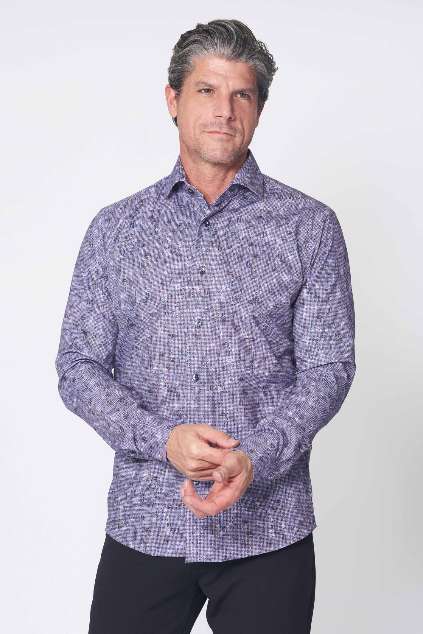 A gray-haired man wears a 7 Downie St. Big & Tall Sport Shirt 18 LS Multi and black pants, standing against a plain white background.