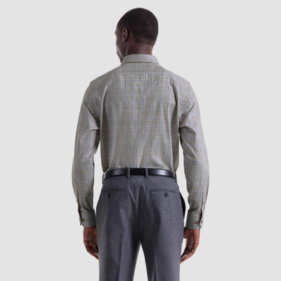 A man faces away, wearing the Bugatchi Axel Grid Sport Shirt HS3285L7S by Bugatchi— a spread collar, 100% cotton long-sleeve shirt— tucked into gray dress pants with a black belt, set against a plain light background.