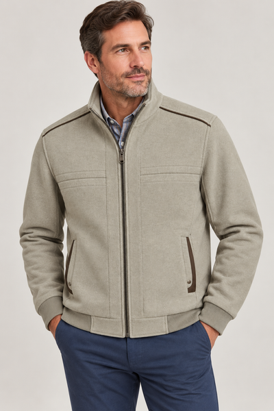A man wearing the Enzo Evan Moto Jacket—a light gray zip-up jacket with brown accents from Enzo—and blue pants stands with his hands in his pockets, looking to the side against a plain background.