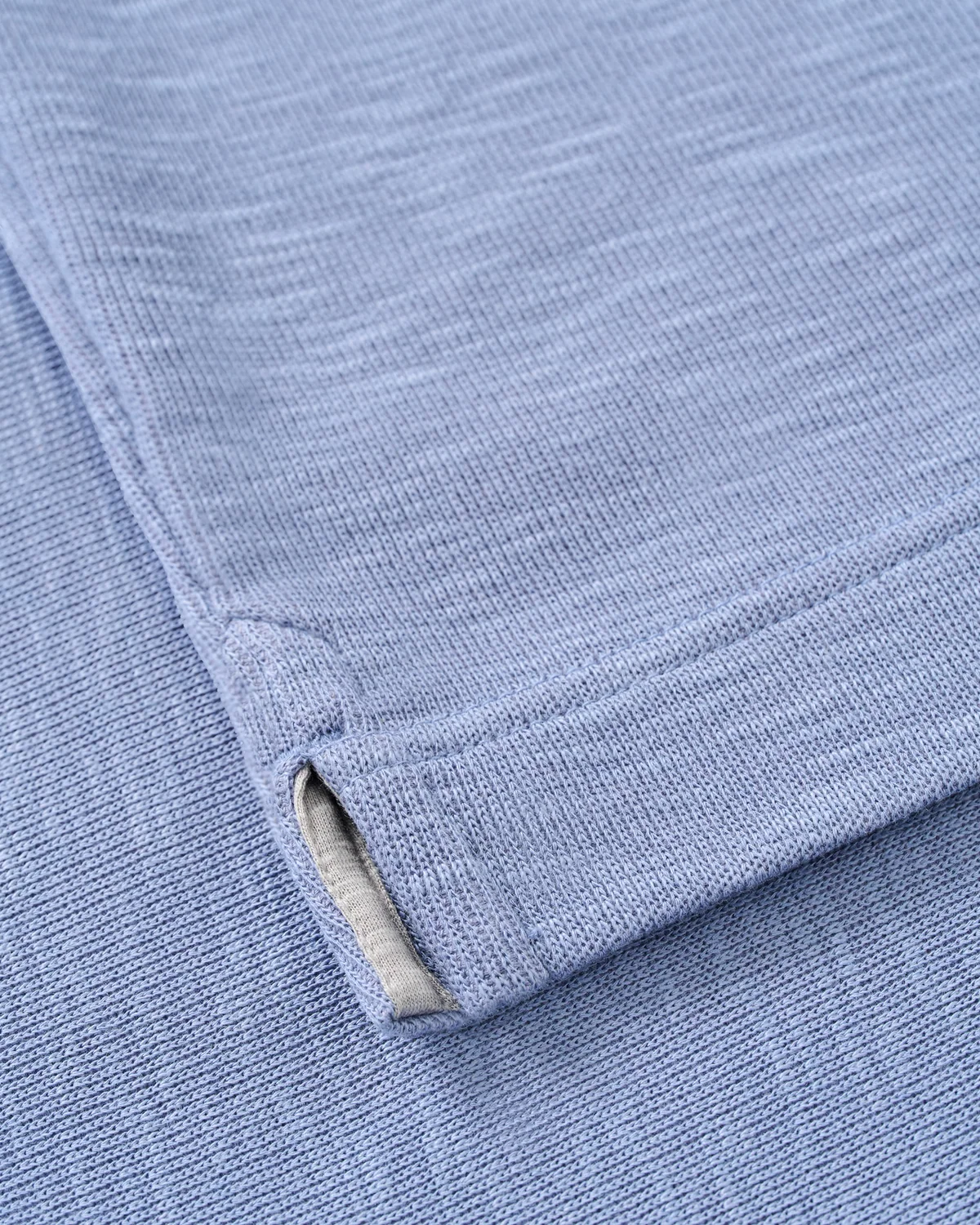 Close-up of the blue moisture-wicking hem and side vent on a Johnnie-O Flame Stitch 1/4 Zip Sweater Big & Tall.
