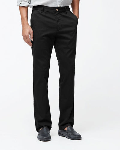 A person wearing Tommy Bahama Boracay Pant Big & Tall chinos, a light gray button-up shirt, and dark loafers stands against a plain white background.