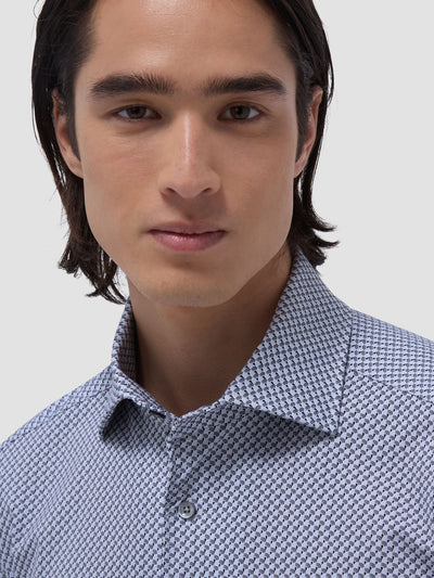 A person with long dark hair wears the Bugatchi LS Devon GF9025K80 Platinum, a light blue patterned button-up shirt by Bugatchi, facing the camera against a plain background.