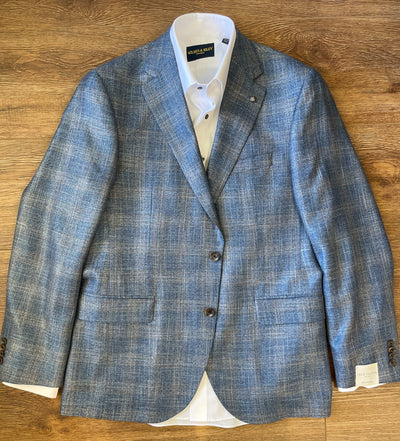 The Jack Victor Sport Coat 1261310, a light blue windowpane jacket with brown buttons by Jack Victor, is laid over a white dress shirt on a wooden surface.