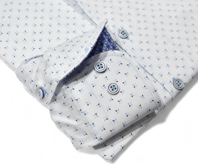 The Marcello OP Star Medallion Sport Shirt W114 by Marcello features a classic fit and long sleeves, with a subtle blue geometric pattern and blue buttons on smooth cotton sateen, neatly folded against a white background.