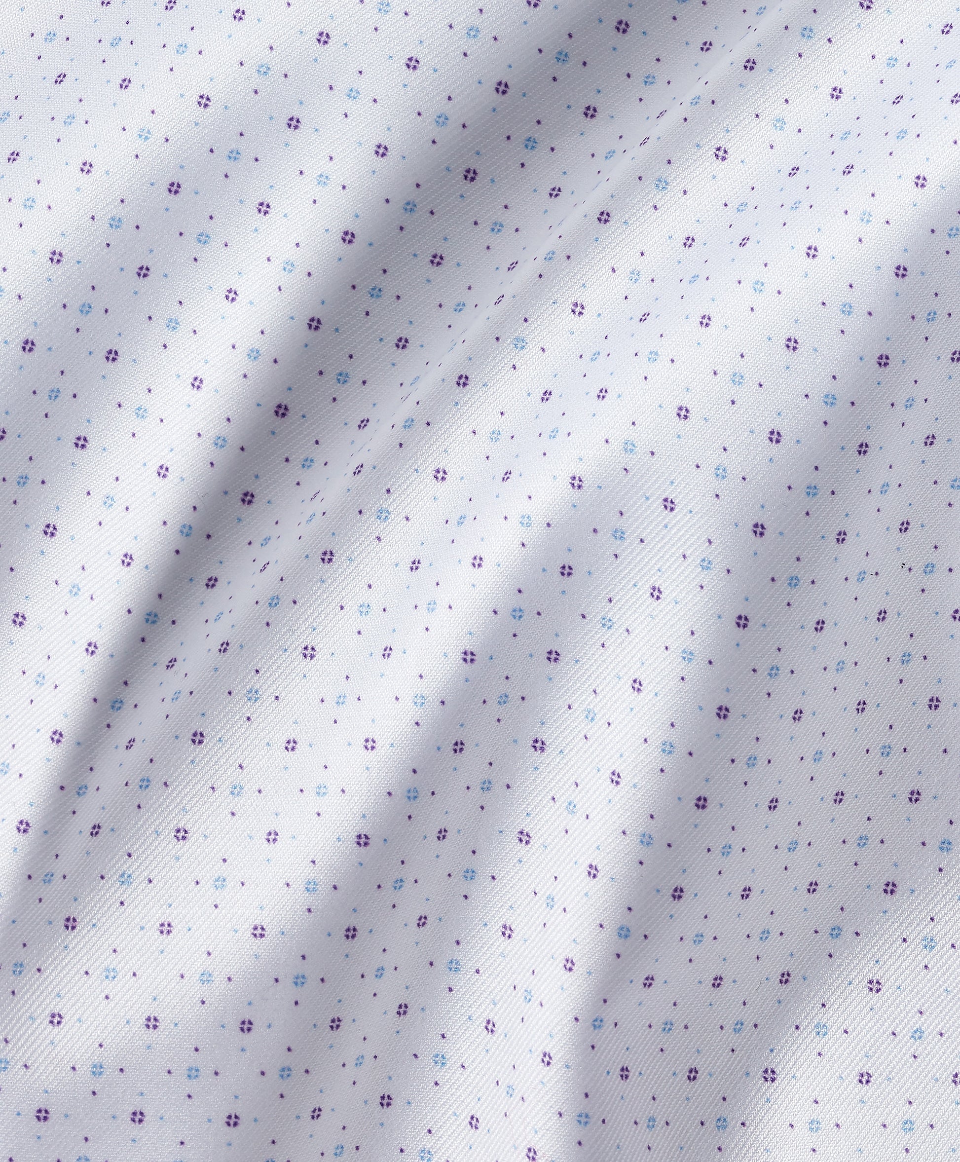 Close-up of white fabric adorned with small, evenly spaced purple floral motifs, displaying gentle folds and texture—evocative of the craftsmanship in the David Donahue Stretch Print Dress Shirt TBSP13200 by David Donahue.