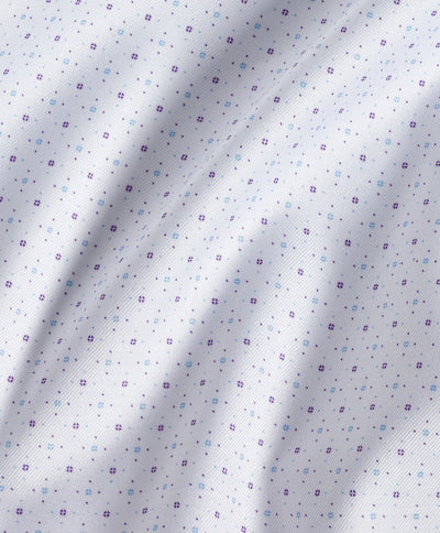 Close-up of white fabric adorned with small, evenly spaced purple floral motifs, displaying gentle folds and texture—evocative of the craftsmanship in the David Donahue Stretch Print Dress Shirt TBSP13200 by David Donahue.