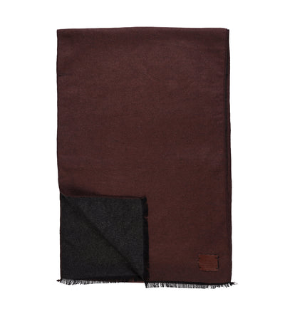 The Amanda Christensen Double Face Scarf 440714 features a rectangular design in dark brown and black wool, double-faced with fringed edges and a small leather patch in one corner, displayed flat on a white background.