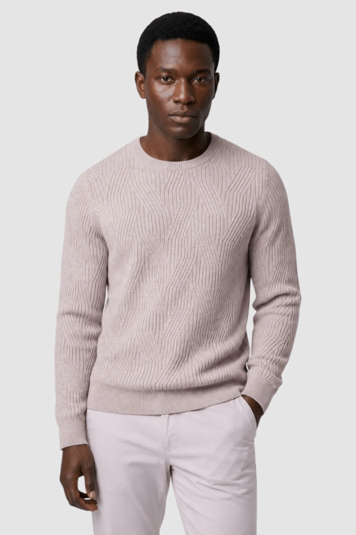 A man stands against a plain light background, wearing the Garnet Garrick Diamond-Pattern Crewneck Sweater 2622010 by Garnet—a textured light beige wool-blend piece paired with matching pants, offering a modern take on men’s fall fashion.