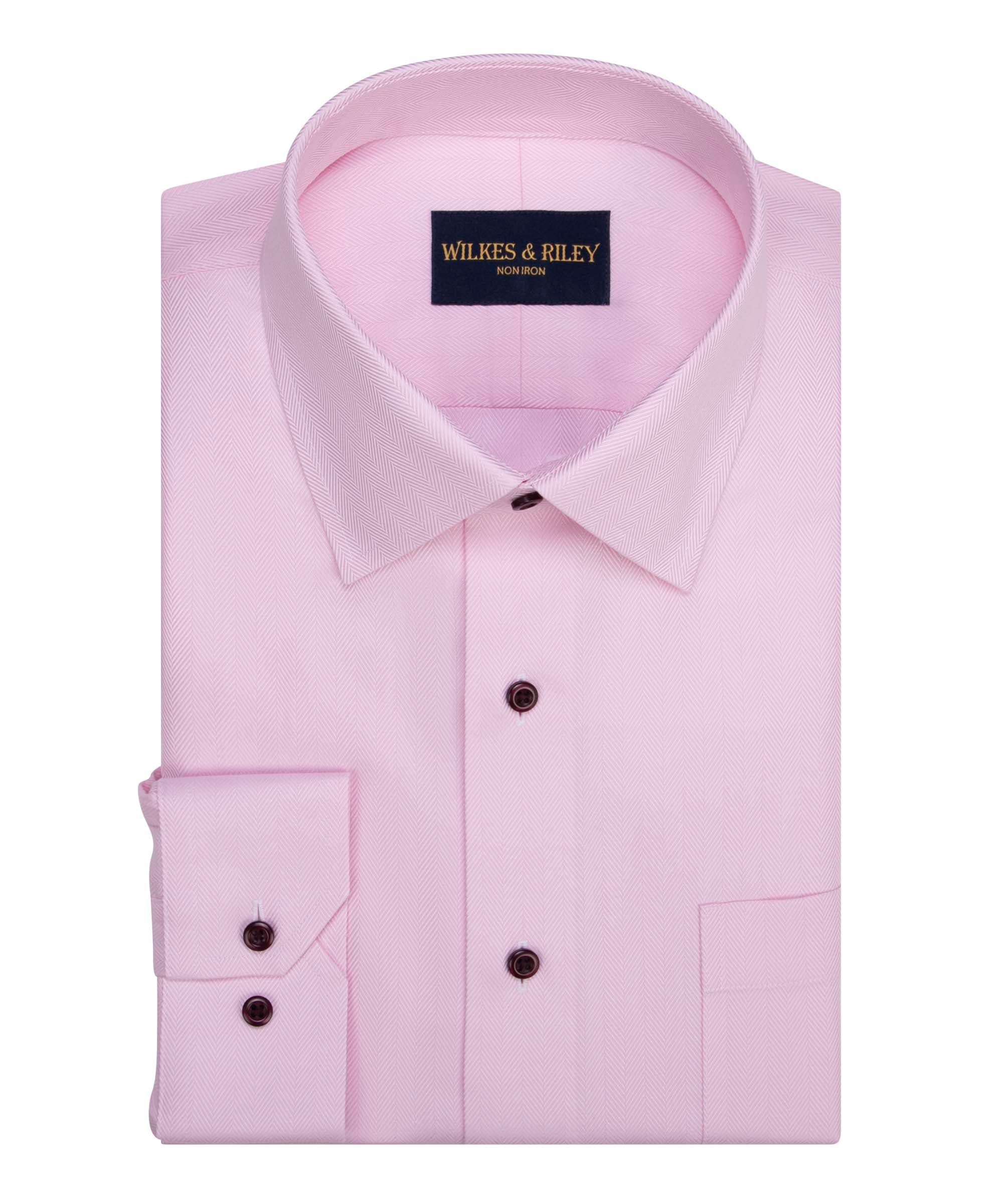 A neatly folded W&R Pink Herringbone B1545 dress shirt by Wilkes & Riley, featuring a light pink color, pointed collar, dark buttons, front pocket, and non-iron fabric.