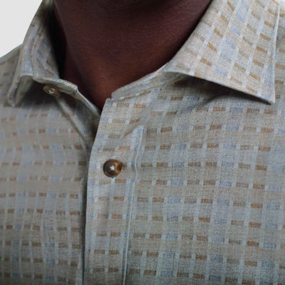 Close-up of a person wearing the Bugatchi Axel Grid Sport Shirt HS3285L7S, a beige and light blue checked long-sleeve shirt with a 100% cotton spread collar by Bugatchi.