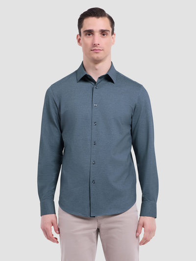 A man wears the Bugatchi James Long Sleeve Shirt HF9556K60 in teal and light beige pants by Bugatchi, crafted from premium fabrics, standing against a plain light background.
