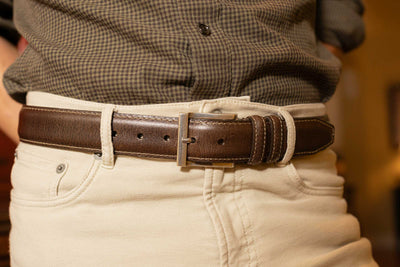 Someone wearing the Martin Dingman Bill Water Buffalo Leather Belt with light-colored pants and a dark plaid shirt.