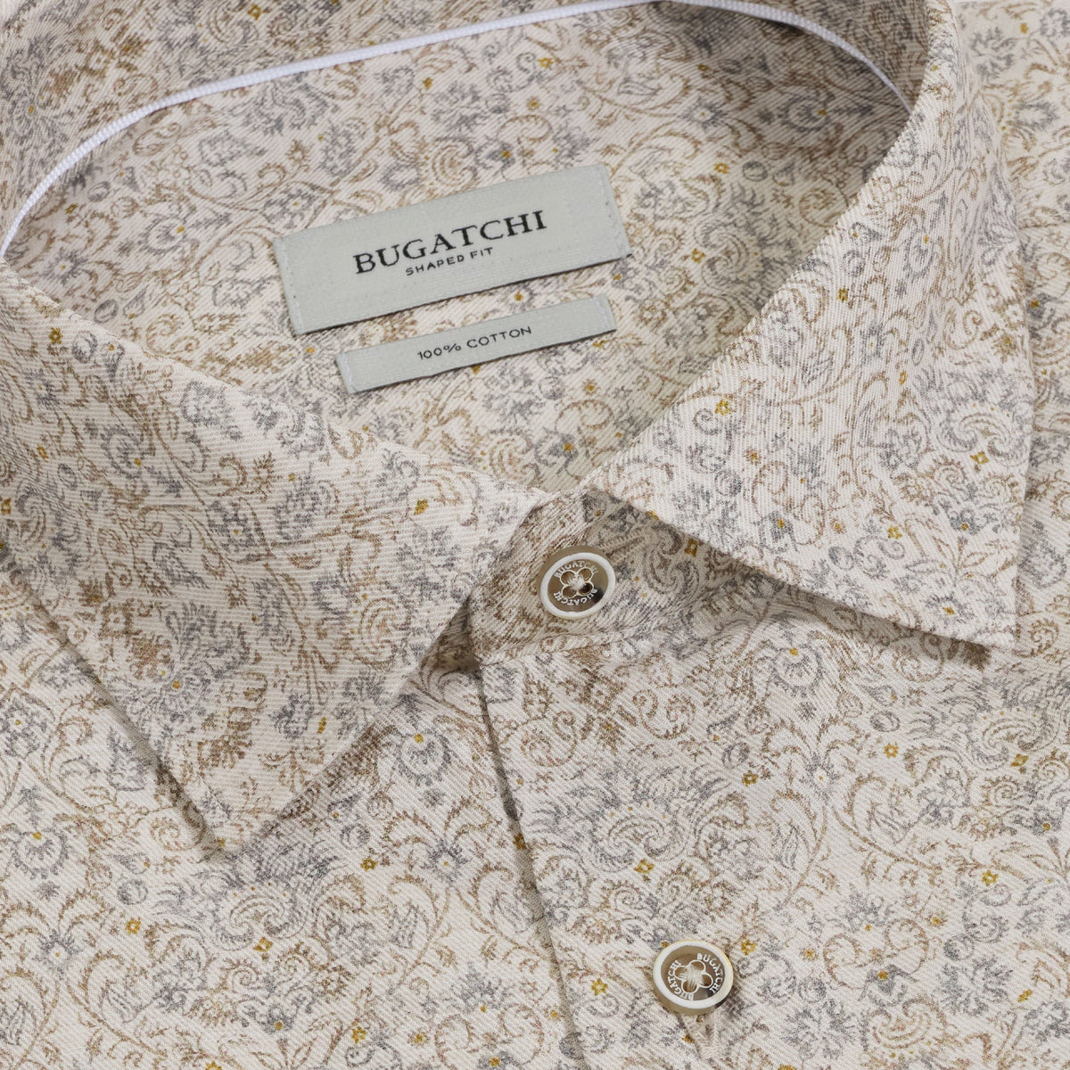 Close-up of the Bugatchi Axel Paisley Sport Shirt KS3132L40S, a long-sleeve Italian cotton shirt featuring a subtle beige, grey, and gold paisley design. The shirt includes a pointed collar and two visible buttons for an elegant, refined touch.