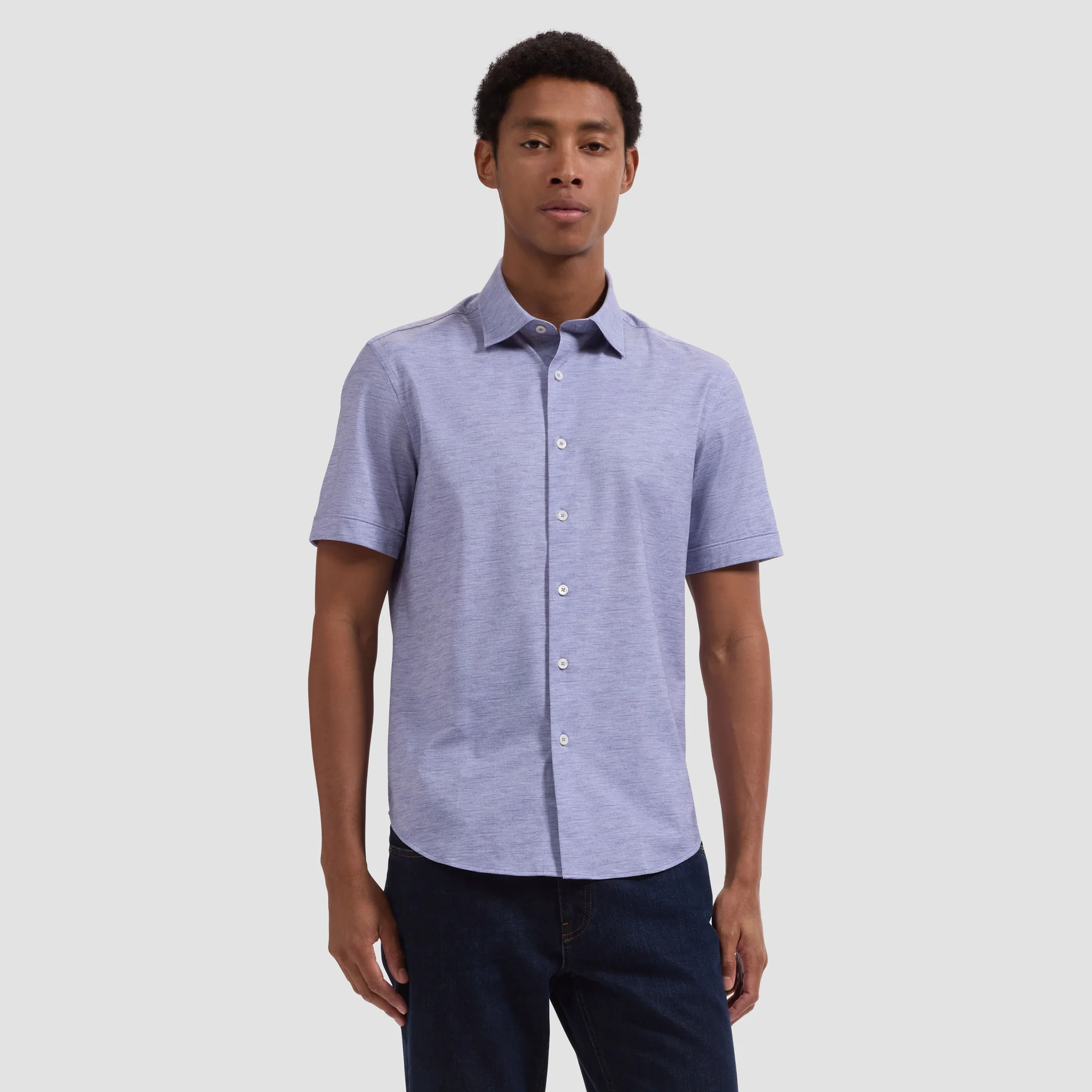 A man stands against a plain background wearing the Bugatchi Miles OoohCotton® Melange Shirt JF9505F40, featuring 8-way stretch, paired with dark jeans.