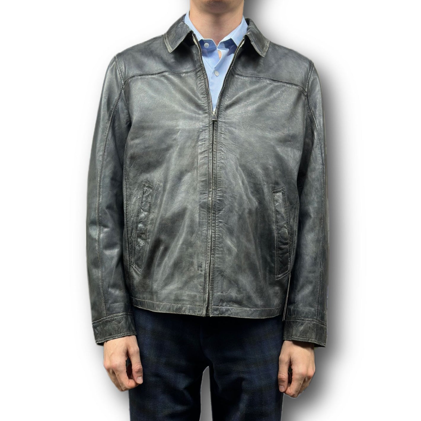 A person is shown from the neck down against a white background wearing the Missani Vintage Leather Jacket 392794 over a blue collared shirt and dark pants.