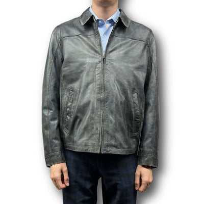 A person is shown from the neck down against a white background wearing the Missani Vintage Leather Jacket 392794 over a blue collared shirt and dark pants.