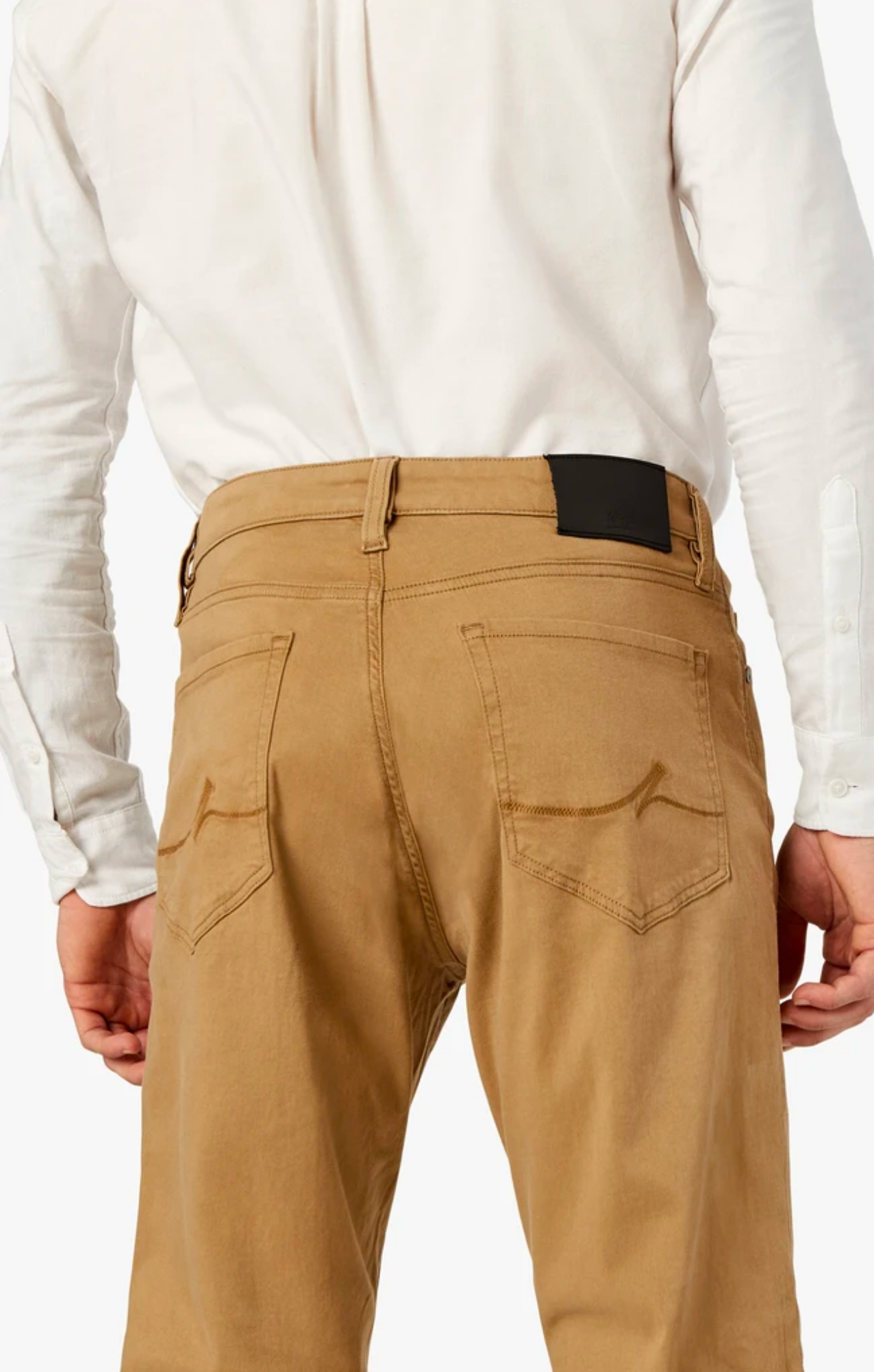 A person is shown from the back wearing 34 Heritage Charisma Khaki Twill straight-leg pants, highlighting the waistband and rear pockets, paired with a white long-sleeve shirt.