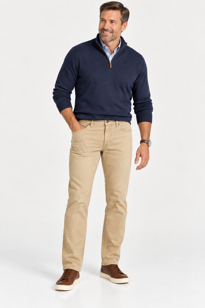 A man wearing a blue quarter-zip sweater over a light blue button-down shirt, Alberto Pipe 1984 Stretch Denim khaki pants, and brown sneakers.