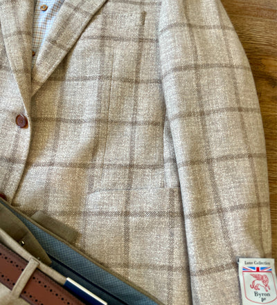 The Byron Luca Sport Coat Windowpane 9526 by Byron features a modern fit in beige plaid with brown buttons, styled with a brown leather belt and dress pants for a refined Luxe Collection look.