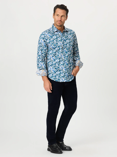 A man stands in a relaxed pose against a plain white background wearing the Robert Graham Euclid Long Sleeve Shirt Big & Tall—a blue and white mosaic print button-down—paired with black pants and black dress shoes.