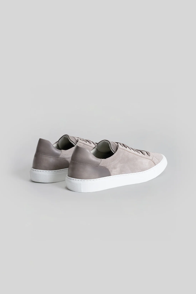 The Robert Barakett Huberto Suede Sneaker features a light gray suede upper, white soles, and darker gray heel panels—an ideal luxury sneaker for those who appreciate subtle sophistication.