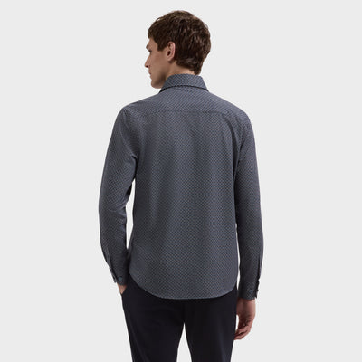 A man with short brown hair, dressed in a dark, long-sleeve Bugatchi Devon Geometric Sport Shirt (KF9431K80) and black pants, stands with his back to the camera against a plain white background.