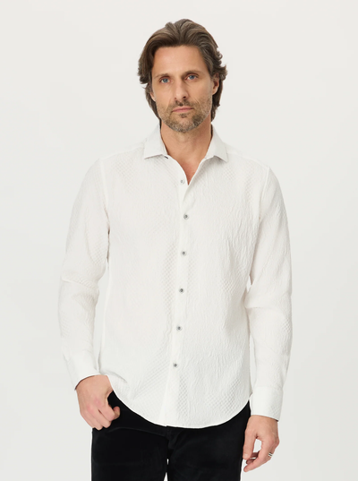 A man with brown hair and a beard is wearing the Robert Graham Devonshire Woven Shirt, a white floral jacquard long sleeve button-down by Robert Graham, paired with black pants and standing against a plain white background.